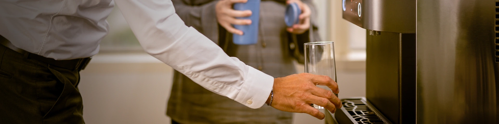 Medewerkers vullen glazen en bekers bij waterdispenser