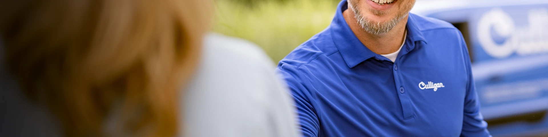 Service medewerker in blauw Culligan-uniform schudt hand met klant