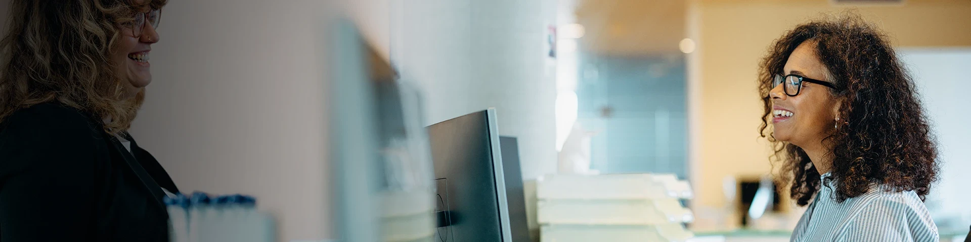 Medewerkster in gesprek met klant aan balie in laboratoriumomgeving