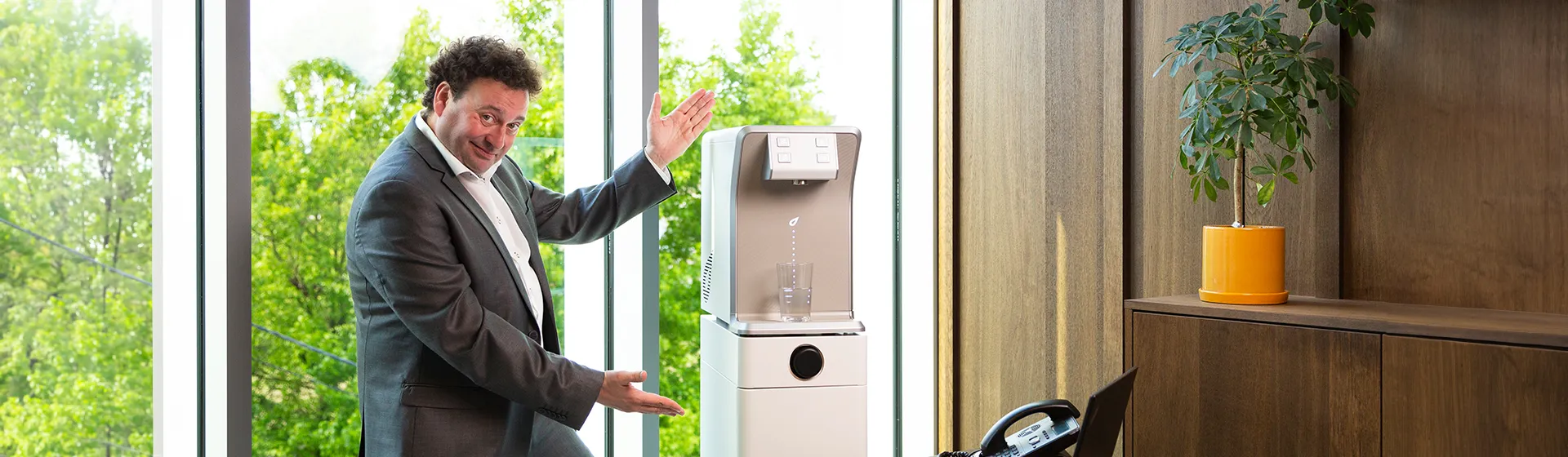 Man toont trots een moderne waterkoeler in kantoorruimte